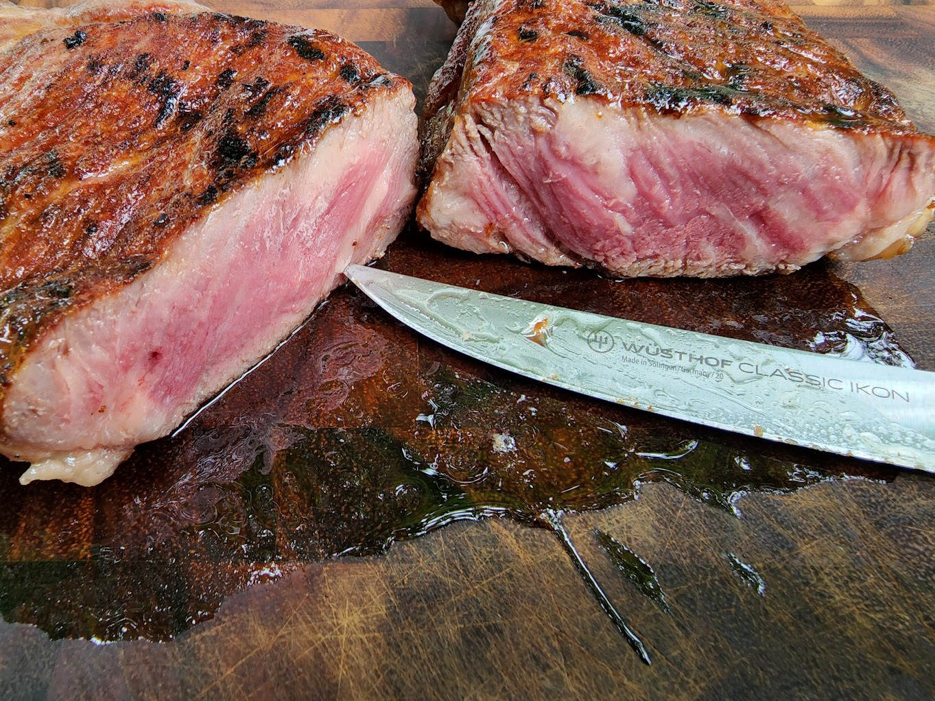 Sliced medium-rare steak resting on a wooden cutting board beside a chef's knife